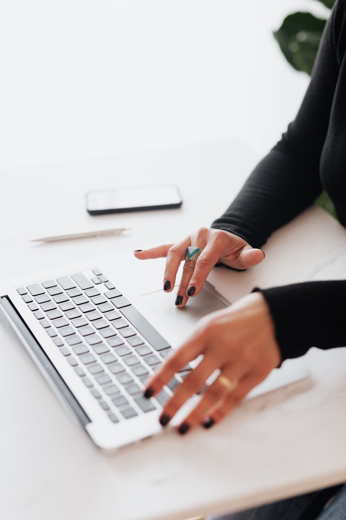 creative A businesswomans hands typing on a laptop at a bright, modern workspace.